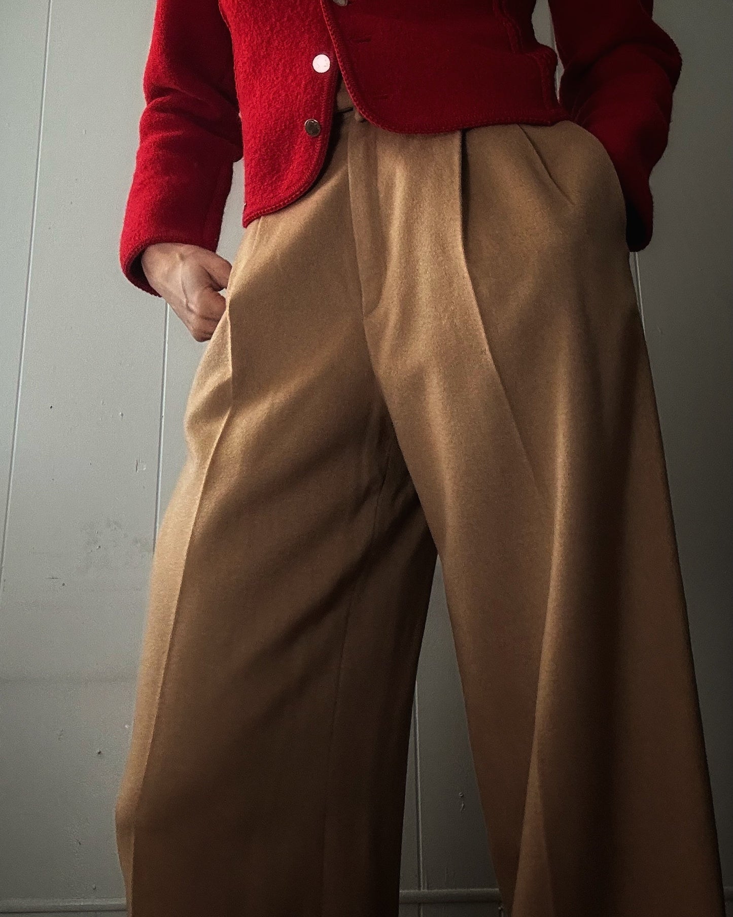 Model wearing camel wool trousers with a red cardigan